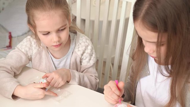 sisters draw on easter eggs with food markers.