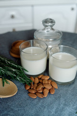 Almond milk in a glass with almonds and rosemary	