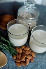 Almond milk in a glass with almonds and rosemary	