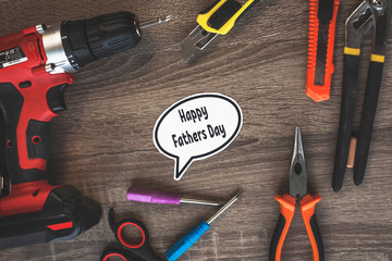 happy father's Day text in the center of a wooden table surrounded by tools