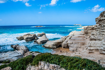 Fototapeta na wymiar A fresh spring wind drives the waves to the coast of Cyprus. The Mediterranean Sea is painted with dark ultramarine and a luminous azure from the inside. 