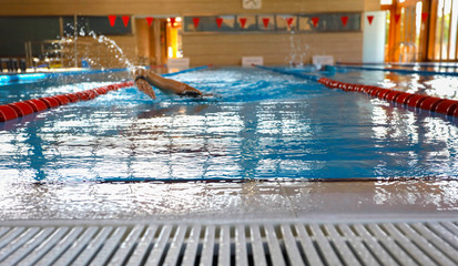 A swimmer swims in an indoor pool.