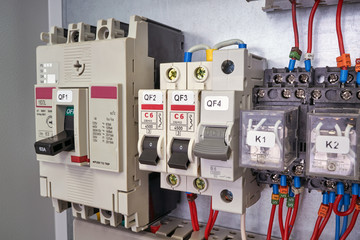 Power circuit breaker, modular circuit breakers and intermediate relays in the electrical Cabinet. Electrical wires are connected to the electrical equipment. Installation, mounting, and maintenance.