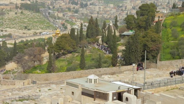 View of Christian tourists people walk by The Orthodox Church of Maria Magdalena on Mount of Olives of Jerusalem in Israel. Also the Dominus Flevit Church and the Zion Jewish Cemetery can be seen.