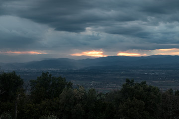 Obraz premium Lumière orangée du coucher de soleil traversant un ciel très nuageux et menaçant au dessus des montagnes des Cévennes (Occitanie, France)