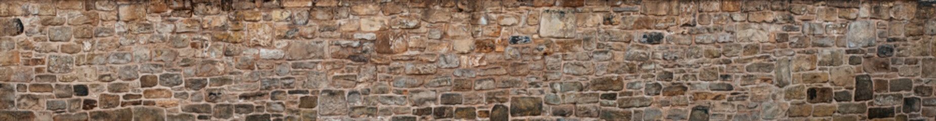 old yellow and brown sandstone wall made of blocks of irregular shape  background