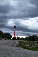 Grande antenne rouge et blanche du Mont Bouquet sur fond de ciel très nuageux et menaçant