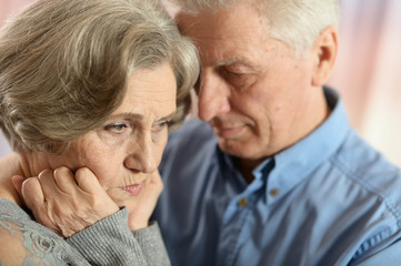 Portrait of sad senior couple posing at home