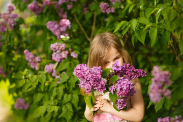 Obraz na płótnie Canvas portrait kid girl in pink dress near lilac flowers