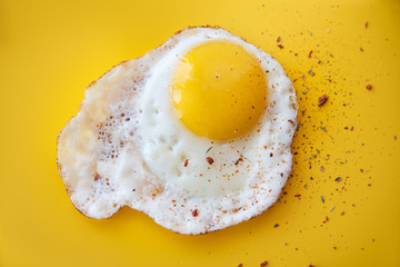 Fried Egg isolated on yellow background (close-up shot)