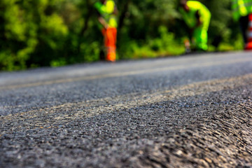 Close up background of a new road that was recently paved with builders in uniform on the back fon