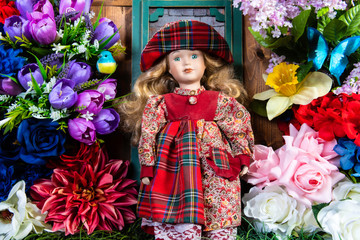 little girl doll in front of green screen door surrounded by colorful flowers