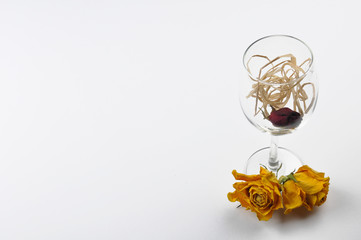 A wine glass and dried roses isolated on white background. Table decoration. Copy space.