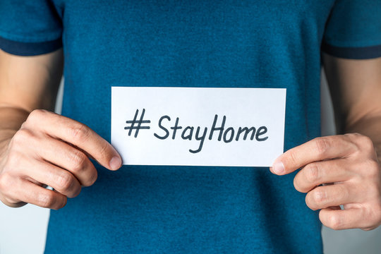 Man holding sheet card with text Hashtag Stay home to stop COVID-19. Quarantine, outbreak alert. Global pandemic coronavirus concept