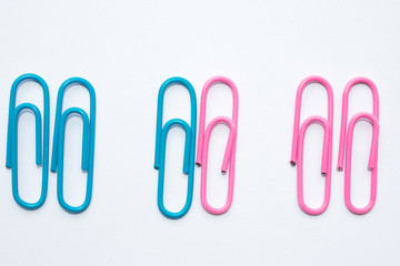 Multi-colored paper clips are arranged by color depending on the color, the office is blue and pink