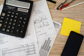 Overall shot of calculator with pens, pencil, stickers, mobile phone, credit card and documents