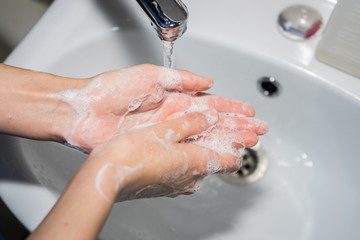 Fototapeta premium washing hands with soap. girl washes her hands to prevent coronavirus covid-19 2019-ncov