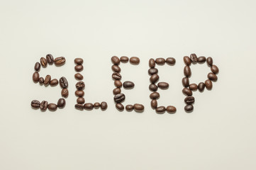 Coffee beans spelling out the word "sleep" against a white background