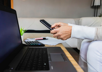 a woman looks at the phone on the work table. work at home concept