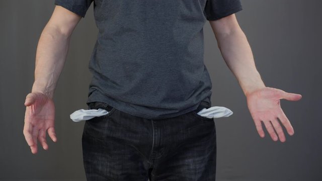 Penurious man twisting empty jeans pockets. Poor man showing empty pockets. Poverty, unemployment and money lack during world financial crisis