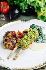 Restaurant dish on a wooden background with vegetables. Lamb ribs in spices and sauce on a plate.