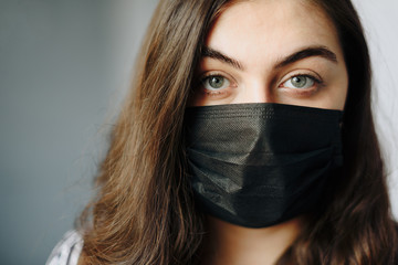 large portrait of a beautiful girl in a black medical mask