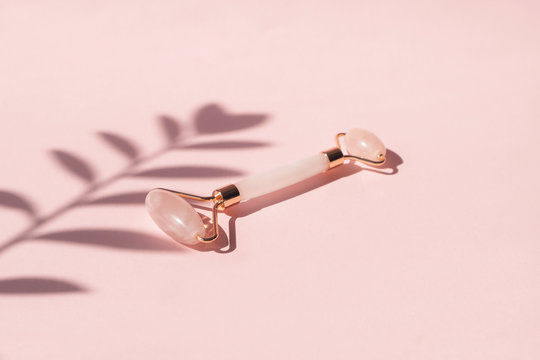 Massage quartz roller for the face of pink natural nephritis. Gua Sha massage tools. Anti age and  lifting at home. Skin care facial massage and relaxation concept. 