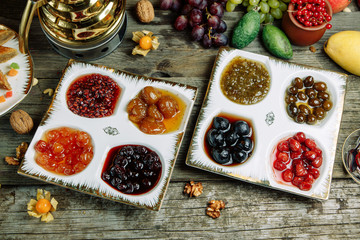  Restaurant dish with vegetable decor on a wooden background. Jam in a glass saucer. Jam of berries and ripe fruit.