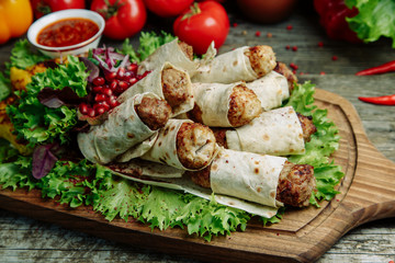 Restaurant dish on a wooden background with vegetables. Lula kebab in lavash with pomegranate and onion on a wooden Board.
