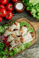  Restaurant dish on a wooden background with vegetables. Lula kebab in lavash with pomegranate and onion on a wooden Board.