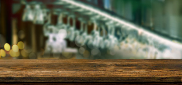 Empty wooden table in front of blurred bar background with light and bokeh for product montage display. Mockup for your product.