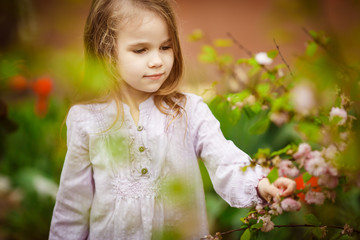 kid girl in garden with pink almond bush