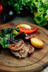 Restaurant dish on a wooden background with vegetables. Steak with vegetables and peppers on a wooden Board.