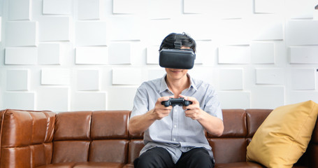 Senior Asian man using tablet and virtual reality simulator playing games in living room and feeling happy . Lifestyle Senior family at home concept.