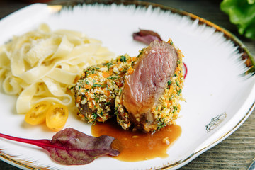  Restaurant dish on a wooden background with vegetables. Beef medium reir with macaroni on a plate.