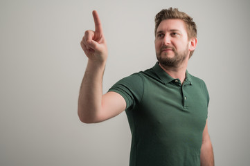 Fototapeta premium Portrait of serious stylish attractive man with thick beard, dressed in casual green t shirt using touchscreen