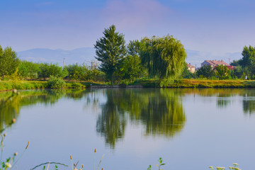 landscape with lake, trees and blue sky with clouds