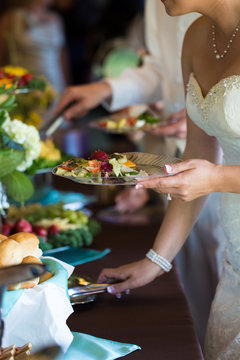 Bride and bridal party serving food on wedding day at buffet