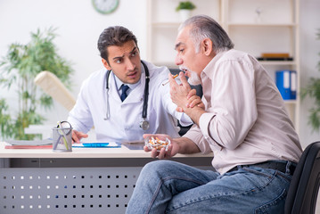 Obraz premium Young male doctor and old patient in antismoking concept
