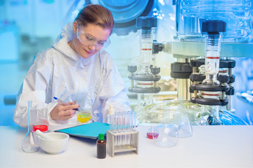 Laboratory assistant in a protective suit and glasses on the background of a laboratory bioreactor. Fermentation process. Microbiological examination. The process of microbiological synthesis.
