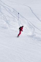 Naklejka na ściany i meble Snowboarderdescends on snowy ski slope after snowfall at winter day