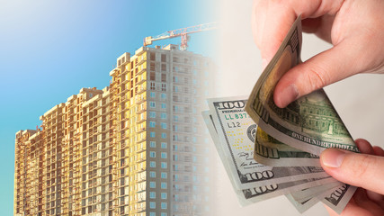 A person counts money against the background of a house under construction. Primary real estate...