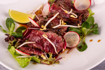 Warm beef salad with terriaki sauce, served with radish, lime and fresh salad