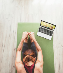 Top view at fit sporty healthy woman sitting on mat in Paschimottanasana pose, doing breathing...