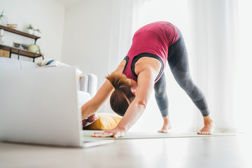 Fit sporty healthy woman on mat in Downward-Facing Dog Adho Mukha Svanasana pose, doing breathing...