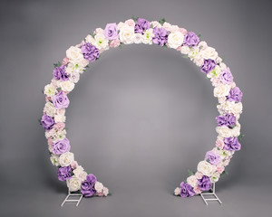 Wedding ceremony decoration on grey background. Beautiful arch with white and purple flower...
