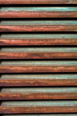 rusted metal slats on a green exterior door, creating an interesting pattern with strong and colorful horizontal elements