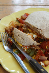 Breakfast, fried eggs, tomatoes, bell pepper, vegetables and bread on yellow plate.
