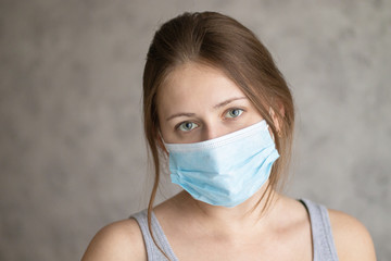 Beautiful young woman wearing face mask because of air pollution, coronavirus or flu. Girl in the medical surgical mask for face protection. Method of preventing an epidemic or pandemic of the virus