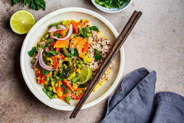 Vegan curry with broccoli, pepper, green beans and brown rice in a bowl, top view.